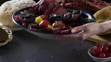 Meat cutting on plate with tomatoes. Scene. Close up of plate with exquisite cut ham and meat with tomatoes. Meat culinary dish on background of fresh herbs and bread video