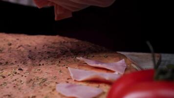 chef bereidt zich voor een pizza, zetten ingrediënten Aan de deeg. kader. traditioneel Koken van Italiaans pizza video