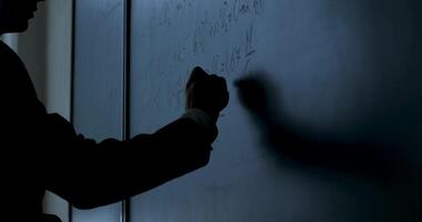 Scientist writing formulas on chalkboard. Hand with chalk wrote physics formulas on black chalkboard closeup video