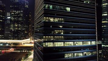 Exterior of modern skyscrapers with luminous windows of offices of megapolise in evening. Shot. Concept of life in big city. Top view of offices of high-rise building in city center at night video