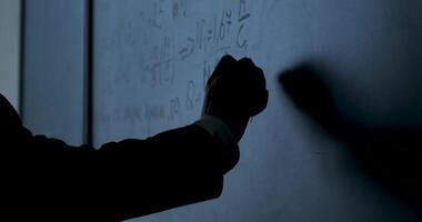 Scientist writing formulas on chalkboard. Hand with chalk wrote physics formulas on black chalkboard closeup video