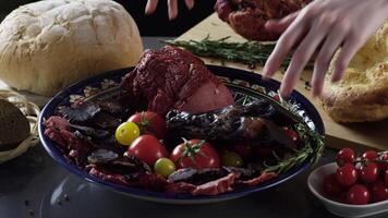 Meat cutting on plate with tomatoes. Scene. Close up of plate with exquisite cut ham and meat with tomatoes. Meat culinary dish on background of fresh herbs and bread video