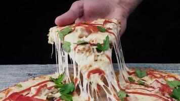 Man takes a piece of pizza with his hand. Frame. Male hand takes the slice of pizza with stretchy cheese video