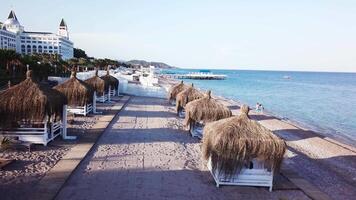 Aerial view of the waves, sandy beach with reed umbrellas. Video. Top view of the sandy beach with natural umbrelas video