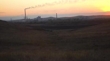 panorama com industrial empreendimento em horizonte. Visão do industrial plantar dentro estepe Campos às pôr do sol. conceito do moderno indústria dentro natural meio Ambiente video