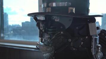 Close-up of detailed robot head of men in hat. Footage. Close-up of robot head in hat sitting on background of panorama of skyscrapers of city video