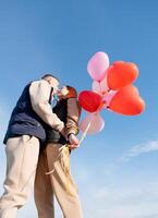 alegre romántico Pareja Fechado y besos al aire libre con globos foto