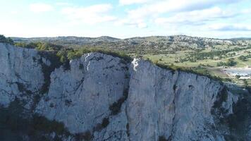 Haut vue de touristes plus de Montagne abîme. tir. fascinant vue de Roche falaise et panorama de vert végétation. groupe de courageux touristes repos plus de falaise contre bleu nuageux ciel video