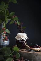a jar of blackberry jam and bruschettas with soft cheese and berries photo