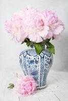 rosado lujoso peonías en un antiguo chino florero con azul ornamento, primavera foto