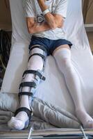 a man with a broken leg in an orthosis on a bed in a clinic after an accident and a fracture of the femur photo