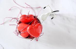 rojo juguete corazones en el espalda de un blanco mini bicicleta en un blanco de madera antecedentes san valentin día concepto, bandera foto