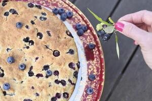 a woman's hand decorates a fresh pie with blueberries, bucking at home,food photo