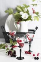 transparent gin and tonic with ice and fresh red currants and blackberries photo