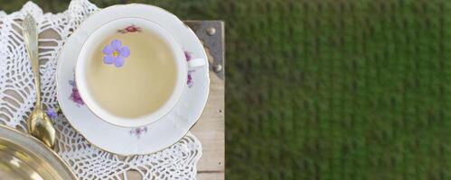 porcelain cup with tea and flower floats in tea, vintage still life, top view photo