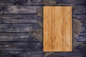 Cutting board on dark wood background, top view photo