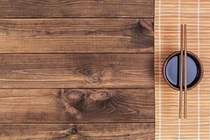 Mat for sushi and chopsticks on dark wooden background. Top view with copy space photo