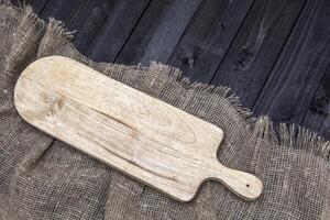 Black wooden table with burlap tablecloth and cutting board, top view photo