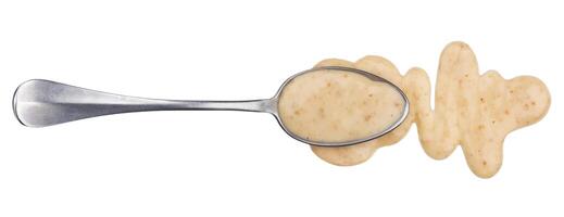 Sesame sauce. Splashes and spilled peanut sauce with spoon isolated on white background. Top view photo