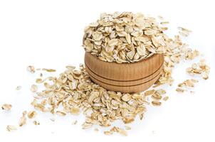 Oat flakes in wooden bowl isolated on white background photo