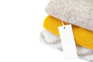 White blank rectangular clothing tag on stack of knitted clothes isolated on white background photo