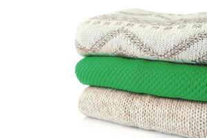 Stack of various sweaters isolated on white background photo