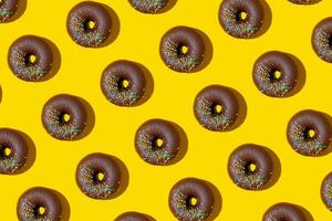 Chocolate donuts pattern on yellow background. Top view, flat lay photo