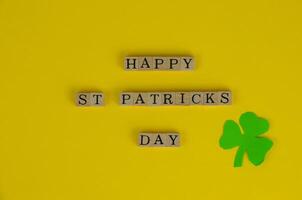 Happy St. Patrick's Day Words on Yellow Background With Three-Leaf Clover Leaf photo