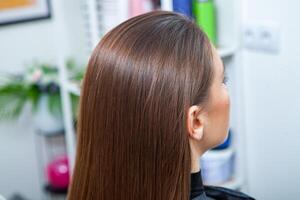 photo of a European girl with long and beautiful brunette hair at the beauty salon. Shiny and healthy hair.