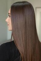 photo of a European girl with long and beautiful brunette hair at the beauty salon. Shiny and healthy hair.