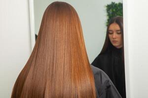 photo of a European girl with long and beautiful brunette hair at the beauty salon. Shiny and healthy hair.