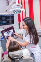 Dentist examining patient teeth in dental clinic. Dentistry and healthcare. Dentist holding dental tools in her hands. photo