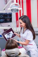 Dentist examining patient teeth in dental clinic. Dentistry and healthcare. Dentist holding dental tools in her hands. photo