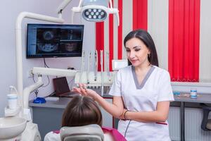 Dentist examining patient teeth in dental clinic. Dentistry and healthcare. Dentist holding dental tools in her hands. photo