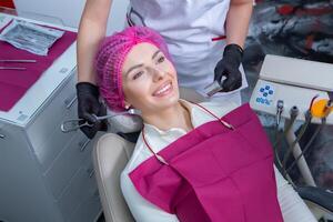 Beautiful woman with healthy straight white teeth sitting at dental chair with open mouth during a dental procedure. Dental clinic. Stomatology photo