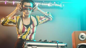 Woman performer mixing sounds at stereo turntables, using audio instruments and disco vinyl to play techno records. DJ musician with crazy makeup using electronics at party. Handheld shot. photo