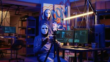 White hat hackers doing online activism, wearing anonymous masks and filming video threatening country government to reveal secret documents as revenge for putting citizens at risk photo