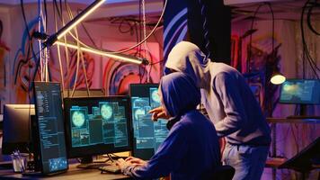 Hackers in neon lit room writing lines of code on computer, having burst of joy after successfully get past security systems with their virus. Scammers happy after finishing working hacking script photo