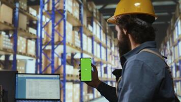 Delivery station associate works with greenscreen display in warehouse depot, checking stock logistics for new parcel shipment. Depot worker shows isolated copyspace template. photo