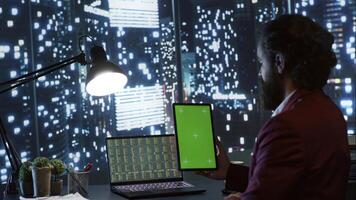 Auditor holding tablet with blank greenscreen display, trying to develop business capital from his office with panorama. Economist looking at blank chromakey copyspace screen on device. photo