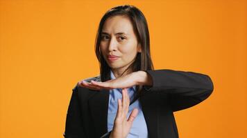 Young woman showing timeout symbol in studio, asking for a break after working hard. Asian person standing over background, presenting pause gesture with hands, confident model. photo