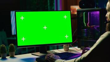 Man chatting with friends online while playing together in multiplayer game on isolated screen desktop PC, close up. Player cooperating with teammates in coop videogame using chroma key monitor photo