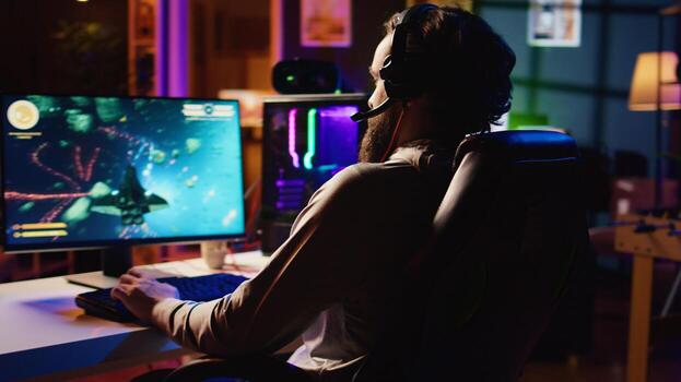 Man at home playing singleplayer videogame with spaceship shooting laser beams at asteroids, panning shot. Pro gamer destroying enemies in science fiction game using gaming mouse photo