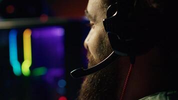 Man talks with teammates online while playing video games on gaming PC, extreme close up. Gamer battling enemies in multiplayer shooter, discussing with other players through headphones mic photo