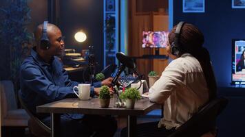 Online show host recording podcast with guest, using analog mixer equipment in home studio living room. Man setting up audio device for live broadcast with woman, ensuring flawless sound quality photo