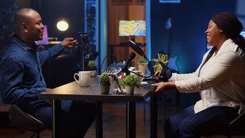 African american man invited to podcast entering studio with host, ready to participate in entertaining discussion. Smiling guest sitting down and putting on headphones for online comedy show photo