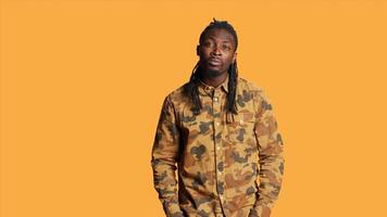 Shocked african american man saying wow on camera feeling amazed by something in front of him. Surprised excited person with dreads smiling in studio over orange background. photo