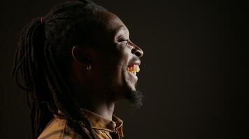 African american guy having fun on black background, laughing at jokes with his colleagues and enjoying free leisure time at the studio. Adult feeling joyful, laughs at funny memes. Handheld shot. photo