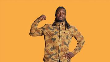 Athletic person flexing his arms muscles in studio and pointing up, showing off his strength and biceps standing over orange background. African american guy indicating upwards direction. photo