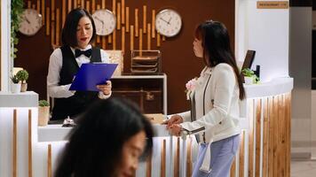 Hotel guest signing registration papers at front desk, confirming room reservation and enjoying five star resort facilities. Asian woman finishing with check in process, concierge services. photo
